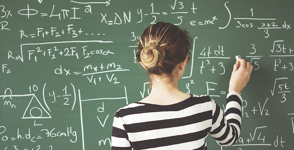 young girl solving math equations on the chalkboard