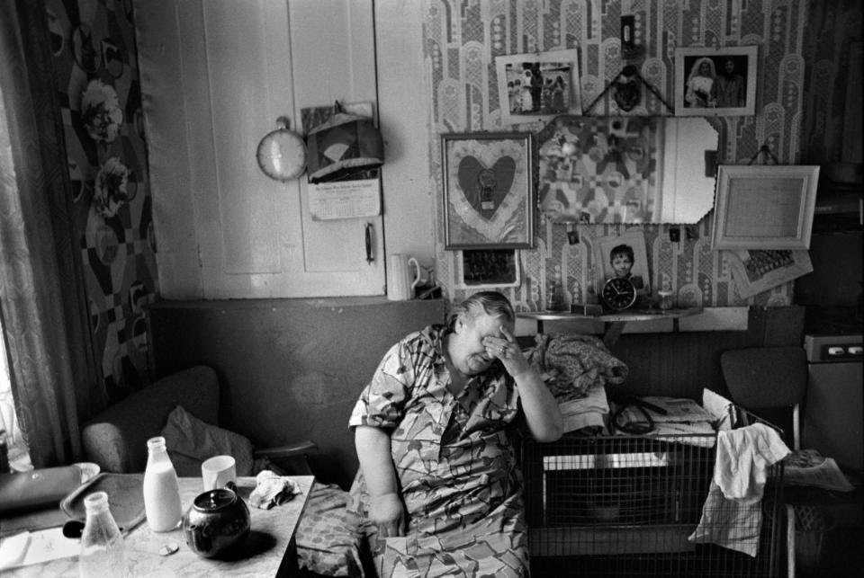 Whitechapel, London, 1975.A resident in her living room covers her eyes, head in hand, exhausted. This crumbling block of flats on the Peabody Housing Estate began to be torn down in the mid-1970s -  @HomerSykes