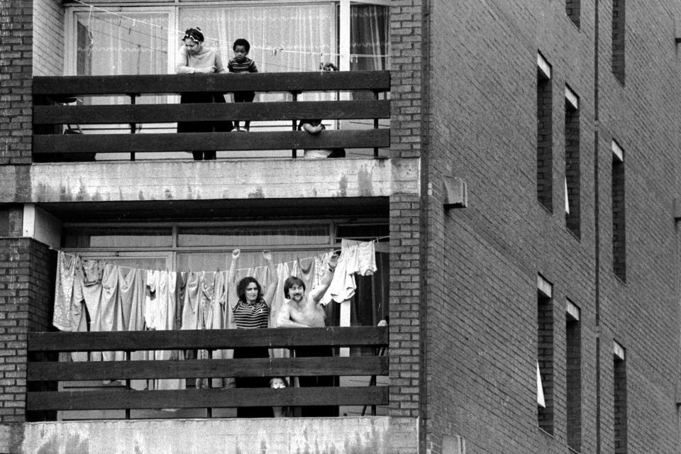Lewisham, London, 1977A National Front supporting family cheer the NF march from the balcony of their tower block flat, while their upstairs neighbour and her two children look on.Photo  @HomerSykes