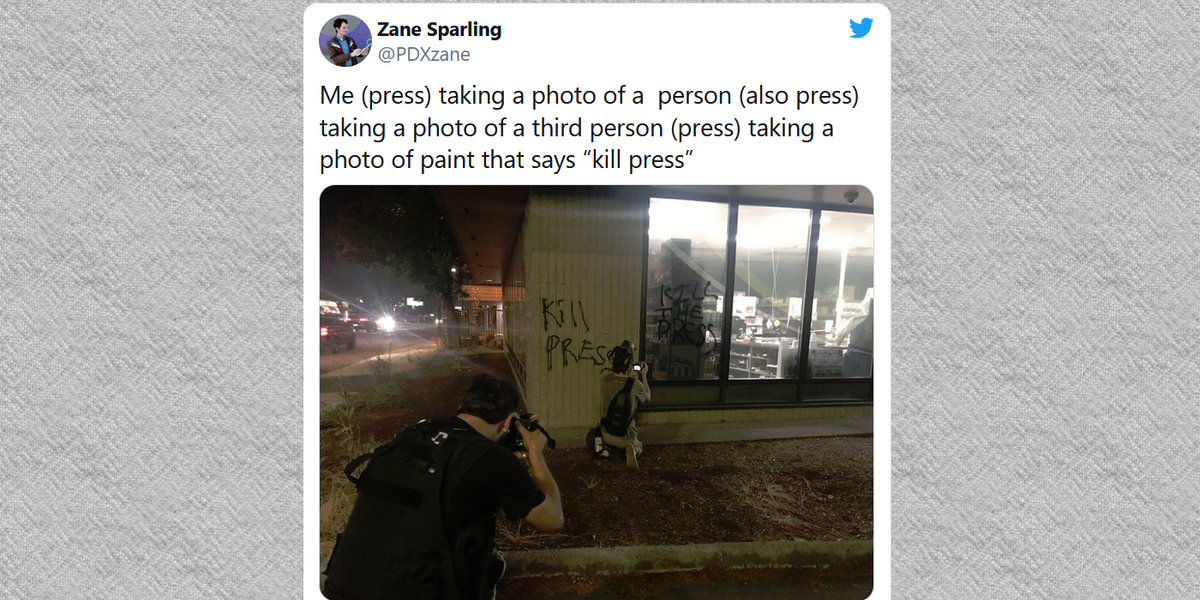 Mathematics, recursion, photography, modern society.  This is a photo of a tweet of Zane Sparling (press) taking a photo of a  person (also press) taking a photo of a third person (press) taking a photo of graffiti that says “Kill Press.”