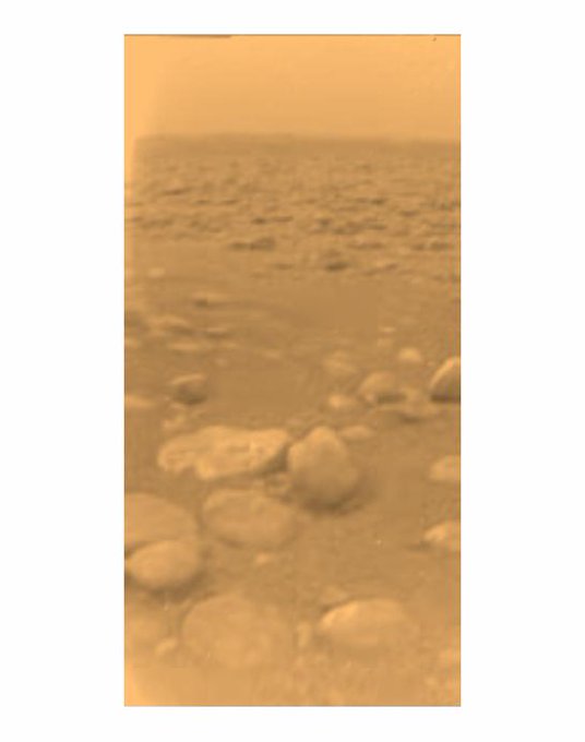 A view of the surface of Titan. Some smooth rocks in the foreground, more rocks in the background across a wide plain. The image is tinted orange and the sky is hazy orange.