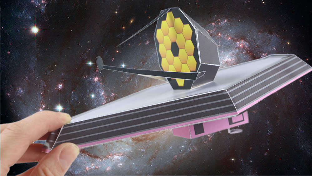 Hand holding an easy-to-build paper model of the Webb Telescope