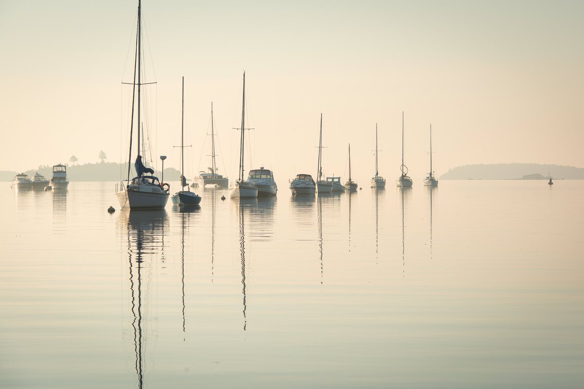 “Morning sun in Mahone Harbour.” Looking out the harbour with Strum Island on the far left and Westhaver Island on the far right. Photo was taken from the front wharf at the Mahone Bay Civic Marina. Great place to come ashore and re-provision. 
44°26.878′ N 64°22.450′ W