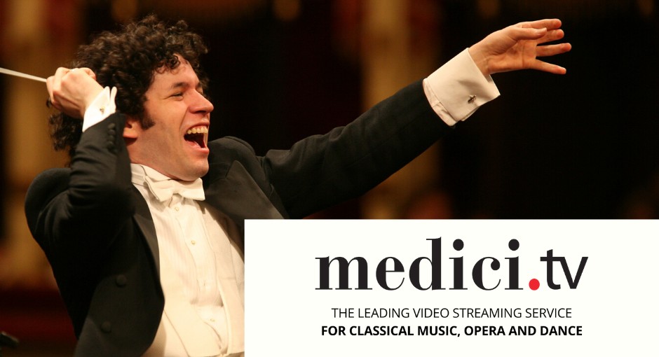 a photograph of a conductor at a concert smiling and gesturing