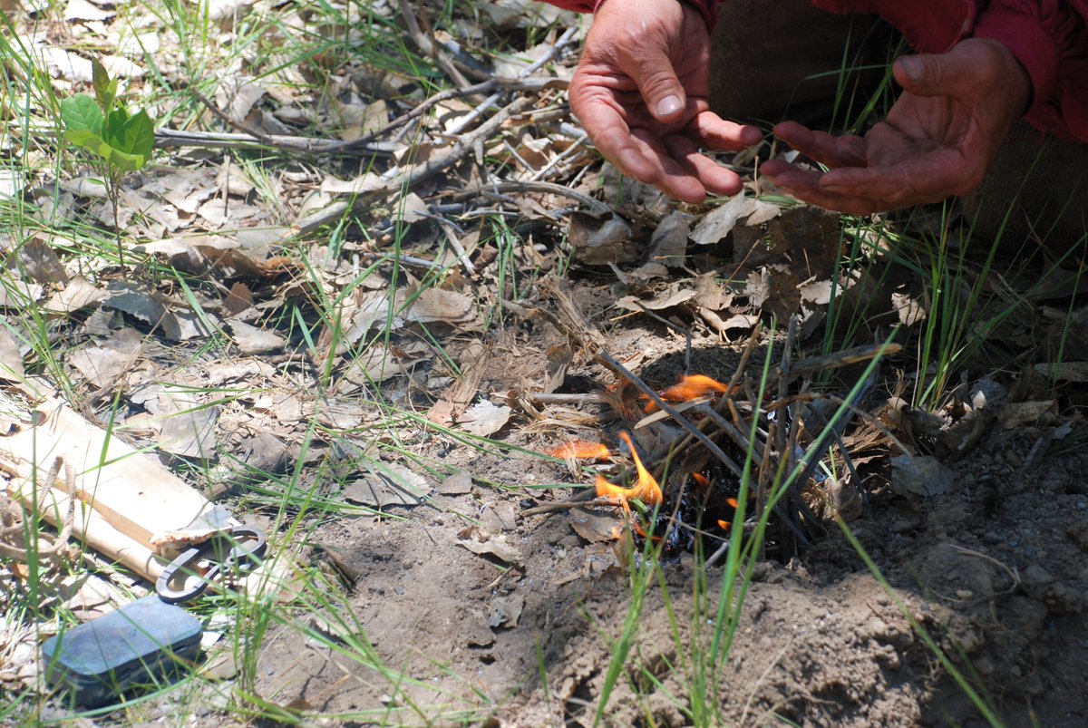 A pair of hands using flint and steel to start a fire.
