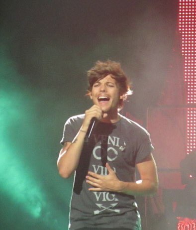 louis tomlinson singing with his hand on his tummy; a thread