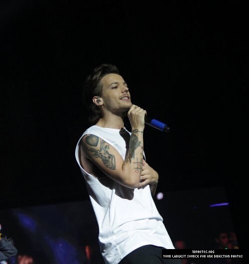 louis tomlinson singing with his hand on his tummy; a thread