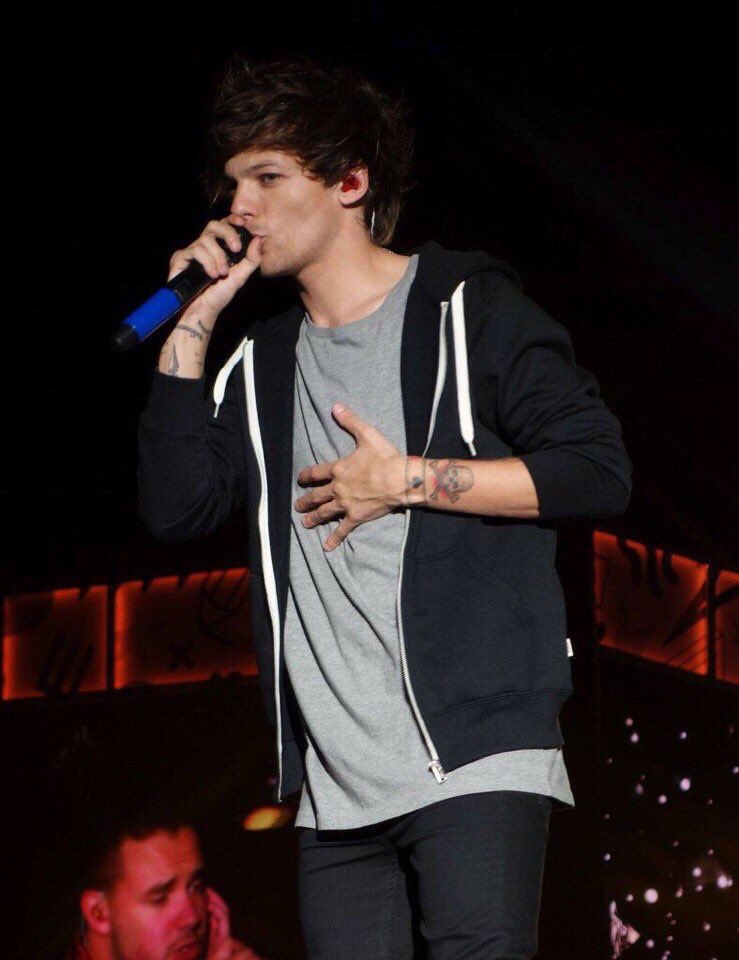 louis tomlinson singing with his hand on his tummy; a thread