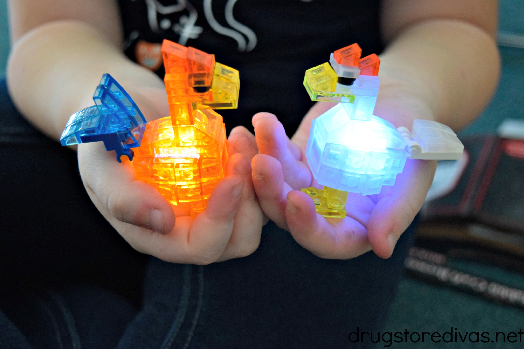 A young girl holding two light up building toys in the shape of a rooster and chicken.