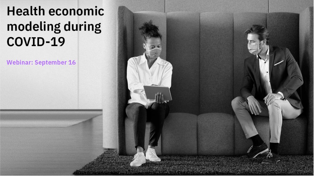 two adults in masks looking at a tablet. 