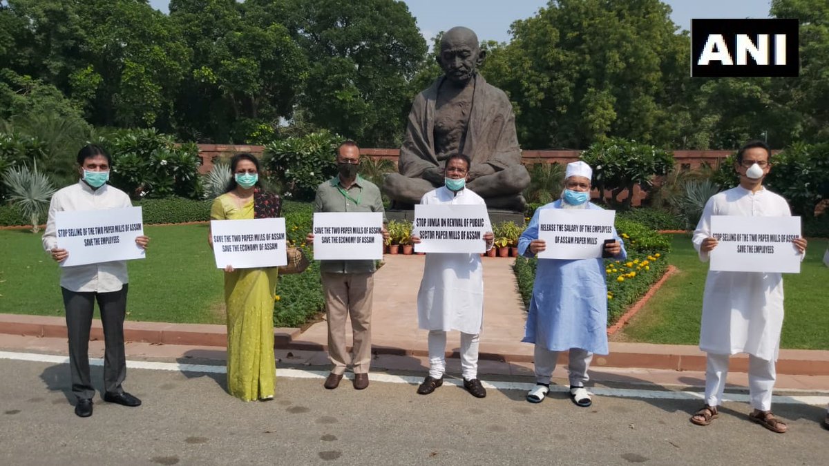 ANI's tweet photo. Delhi: Assam Congress MPs and AIUDF MP Badruddin Ajmal protest in front of Gandhi statue at the Parliament premises and with their demand to save two paper mills of Assam. https://t.co/VMtzJaiftW