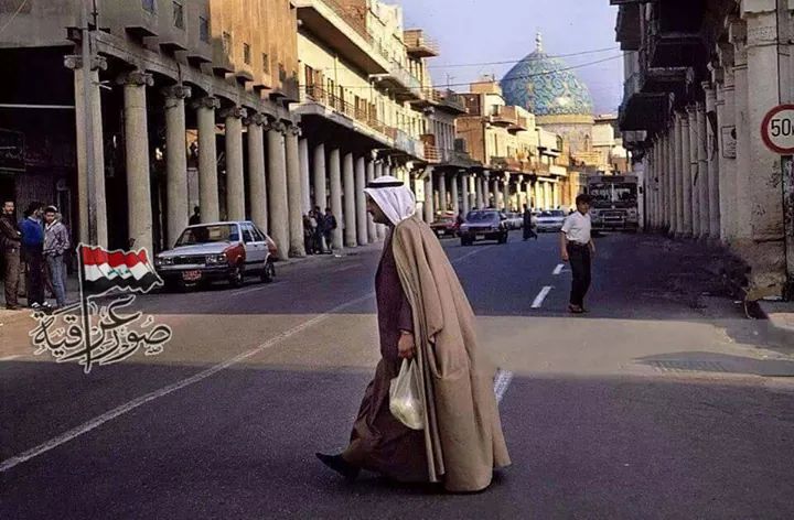 شارع الرشيد البغدادي العريق ونلاحظ نظافة الشارع واحد الماره يهم بالعبور الى احد جوانب الشارع وانسيابية المرور السلسة ونلاحظ قبة جامع الحيدر خانه عام ١٩٩٠