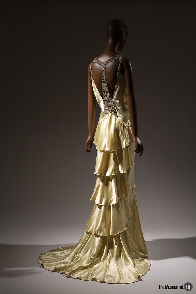 kateStrasdin's tweet photo. The #1930s was certainly fond of a dramatic back. This #AgnesDrecoll evening gown falls in layers of liquid gold #satin but the eye is drawn first to the rhinestone encrusted panel following the length of the spine @museumatFIT #fashionhistory https://t.co/CUf0fCS5BC
