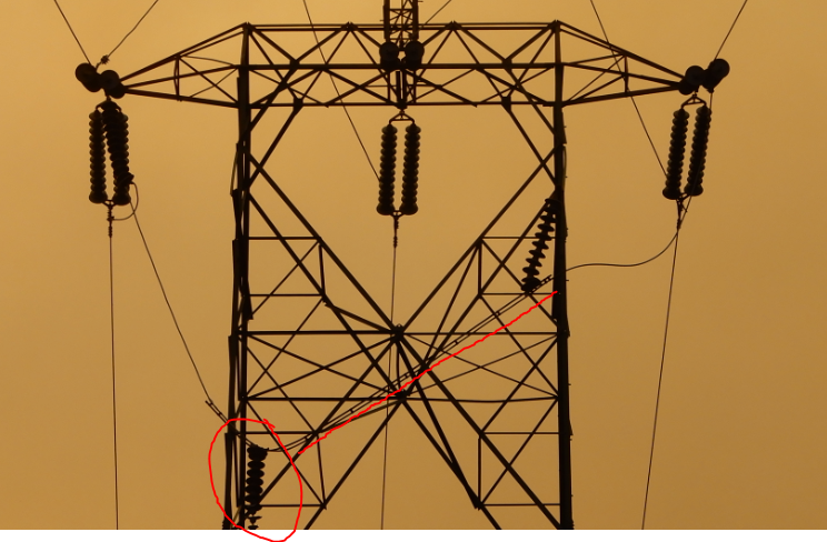 here's the problem. the jumper conductor (the horizontal piece that brings a conductor from one side of the tower to the other) has fallen down. you can see the insulator dangling (circled.) but why did it fall?