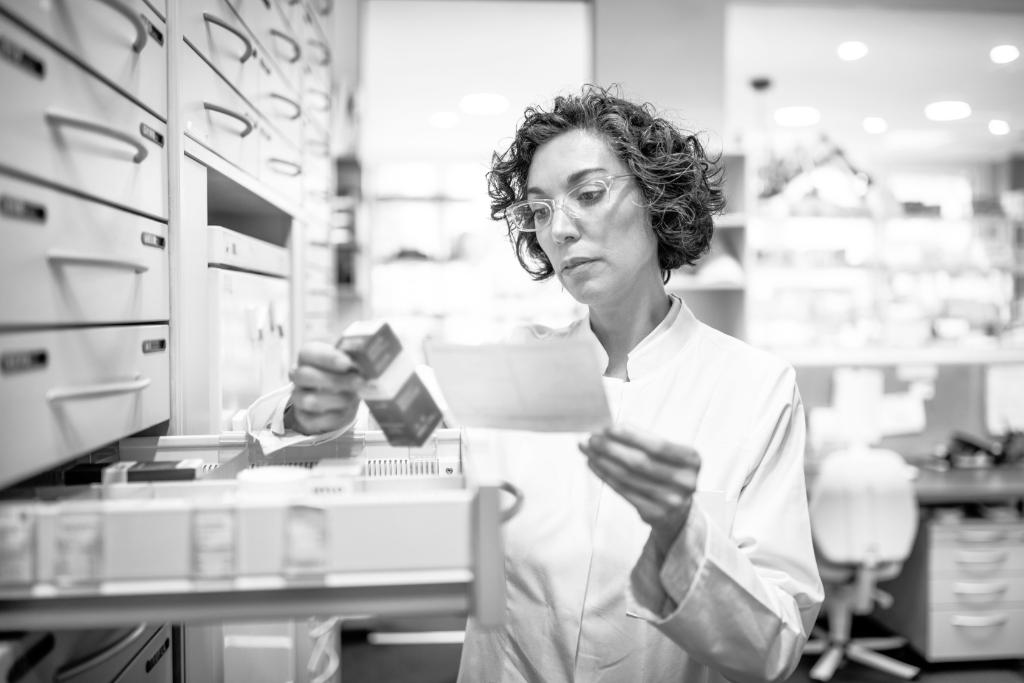 Femal pharmacist looking at medication in drawer.