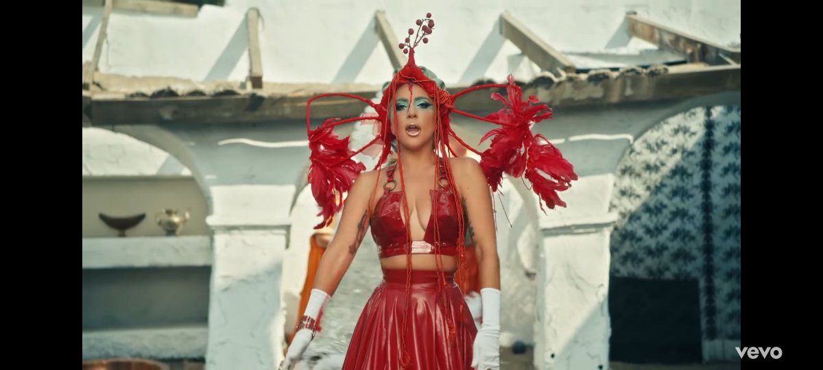 We see then how Gaga with a headpiece that looks like the respiratory system or a bird. They keep trying to get her back to life, the guy approaches to give her CPR (why he opens his mouth) and sort of grabs her ankle to say you're trapped in this cycle (checking her foot irl)