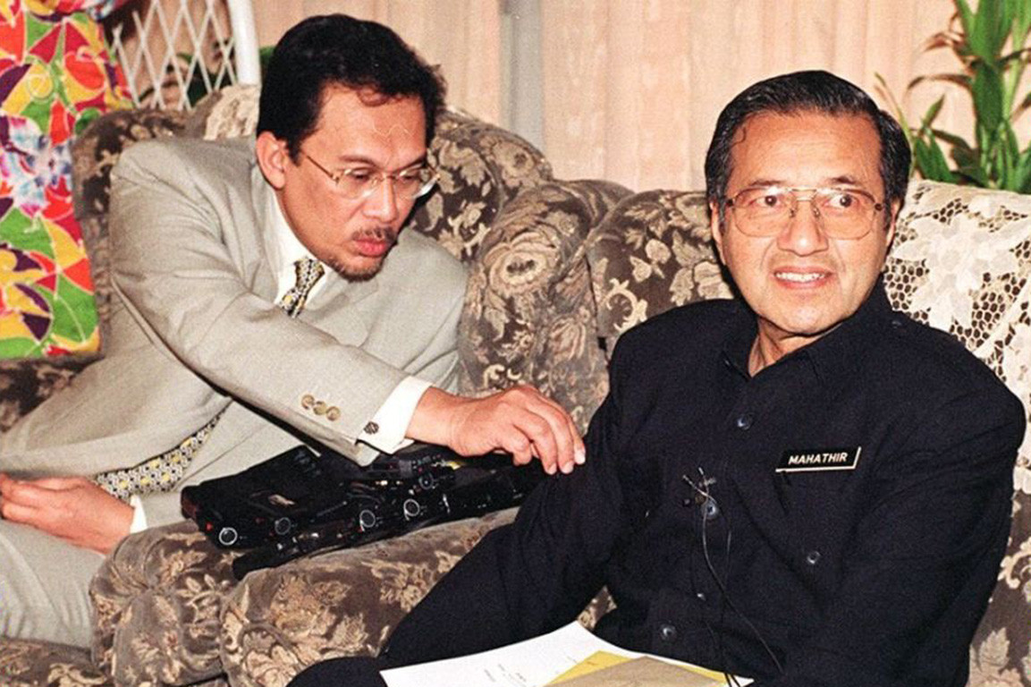 Dalam gambar ini kelihatan Anwar cuba membetulkan sesuatu pada baju Mahathir.Telahan yang kita dapat dimpulkan di sini ialah ada sesuatu pada baju Mahathir yang Anwar rasa perlu dibetulkan.Mengikut lenggok badan, kedua-dua individu ini kelihatan dalam BMI yang normal.