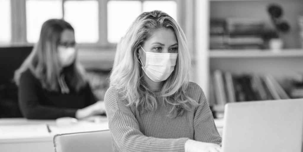 woman in mask typing on laprop