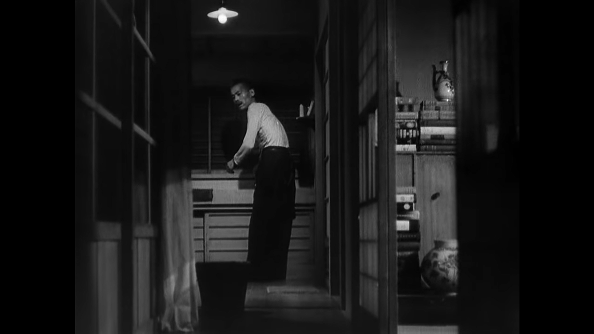 Here's the bathroom, a new angle on the house but with a composition that is nearly identical to the one used for the kitchen and for the hall where we returned to Noriko in the first shot of this scene. Check out the stack of books with vases here peeking out of an unknown room.