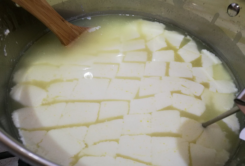 Take the lid off and lo! The milk is now solid. Cut it with the knife in squares. Put it back on the element and heat again on a low flame to 54°C.