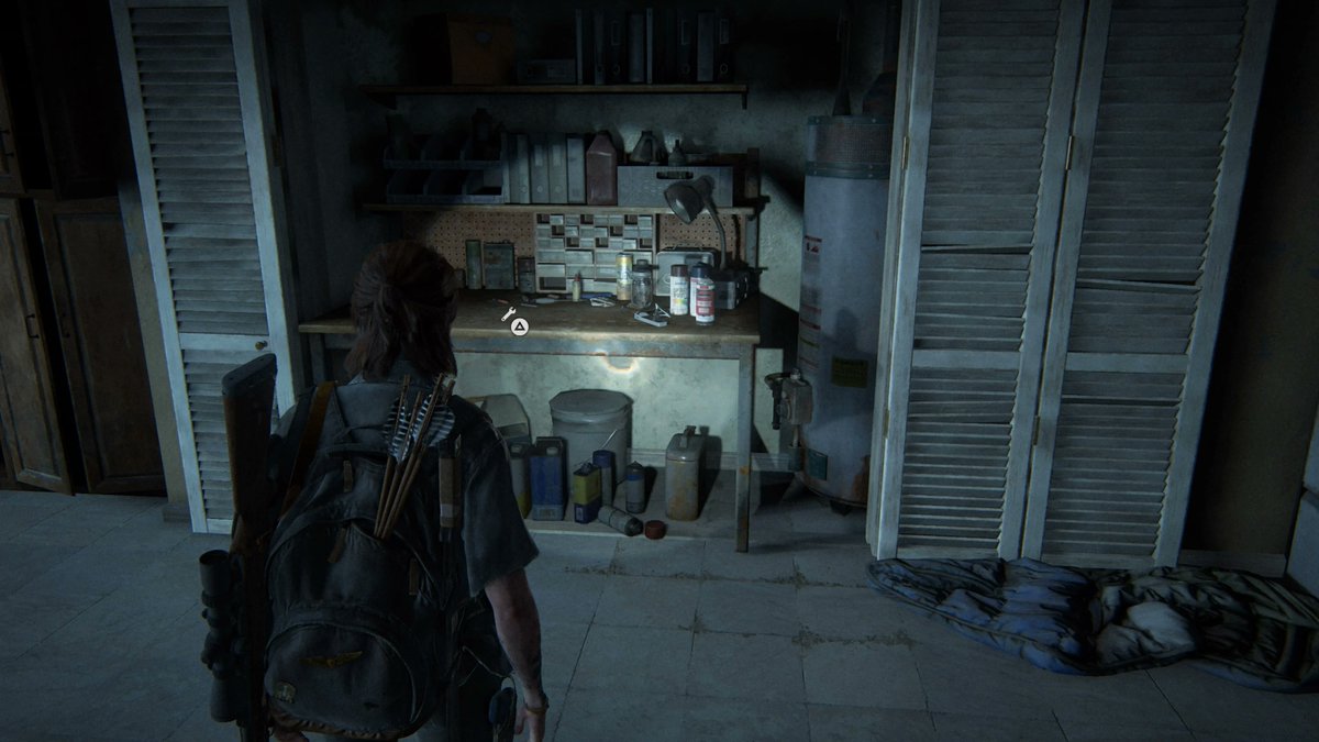 Ellie from The Last Of Us Part 2 looking at a work bench.