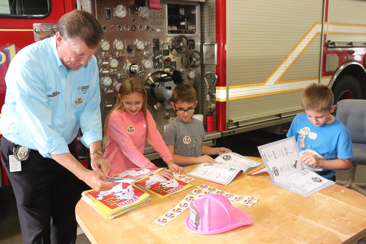 NCInsuranceDept's tweet photo. Insurance Commissioner Mike Causey reviews fire prevention safety in coloring books with a couple future leaders of the fire service! The coloring books were donated as part of @TheBigI_NC Operation EDITH (Exit Drill In The Home) fire safety program! https://t.co/cDup3gegE7