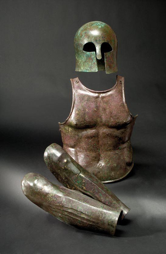 Greek set of armour- a Corinthian helmet, 7th century B.C., a muscle armour breastplate, 5th century B.C. and a pair of greaves, 5th century B.C.E.