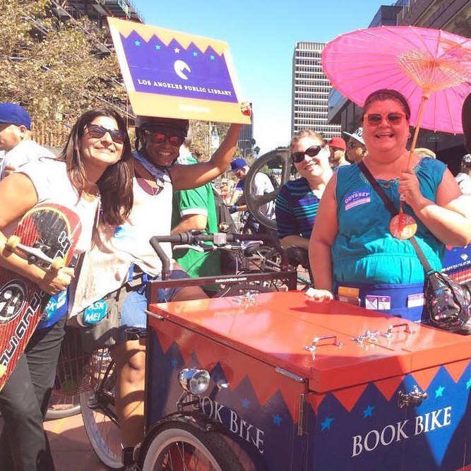 Library staff around the book bike holding up giant library card.