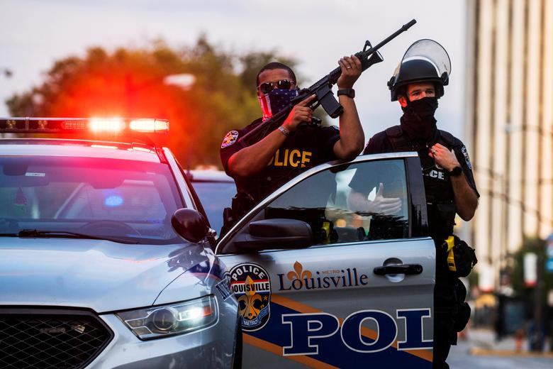 escondidos's tweet photo. #Louisville Police officers stand guard as demonstrators march during a peaceful protest after a grand jury decided not to bring homicide charges against police officers involved in the fatal shooting of #BreonnaTaylor, in Louisville, Kentucky https://t.co/uQZdIkEwqk