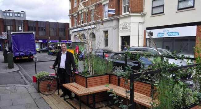 SouthallGaswork's tweet photo. Former Ealing Council Leader Julian Bell unveils his new home - believed to be his third in the borough. 

It's a stylish and well ventilated collection of unwanted Low Traffic Neighbourhood planters, an old bicycle wheel, and stolen park benches where he can carry on lying. https://t.co/OReDxY6ryu