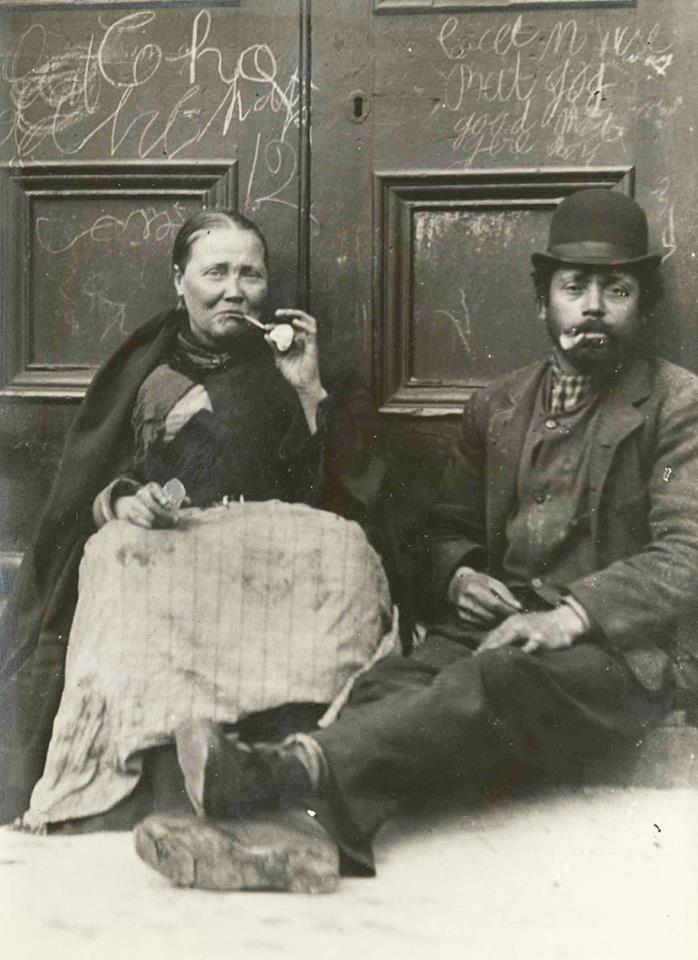 Couple smoking clay pipes in a doorway of Liverpool Custom House, 1885.