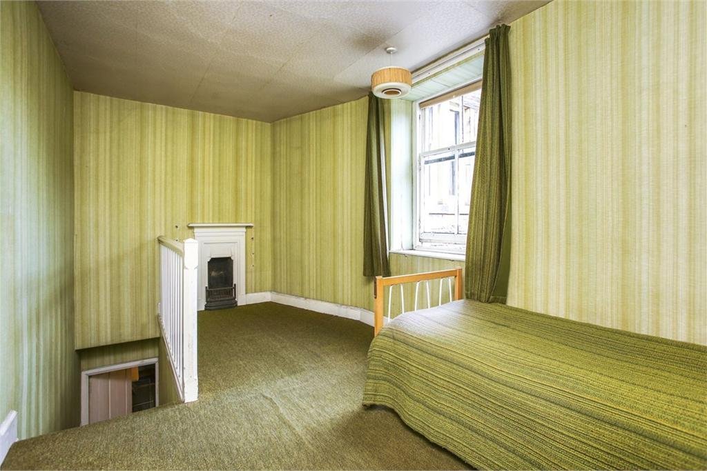 This is that maid's bedroom, note the private stair down to the kitchen, so that they could be kept apart from the main family, and the less-than-generous fireplace. The décor, polystyrene ceilings and lampshade are about the newest thing in this house.