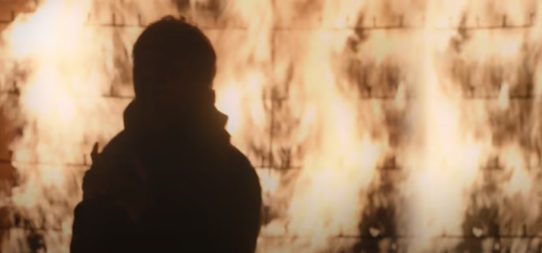 Towards the end, he stands in front of a literal wall of fire - a dramatic and fiery representation of these walls that are coming down.