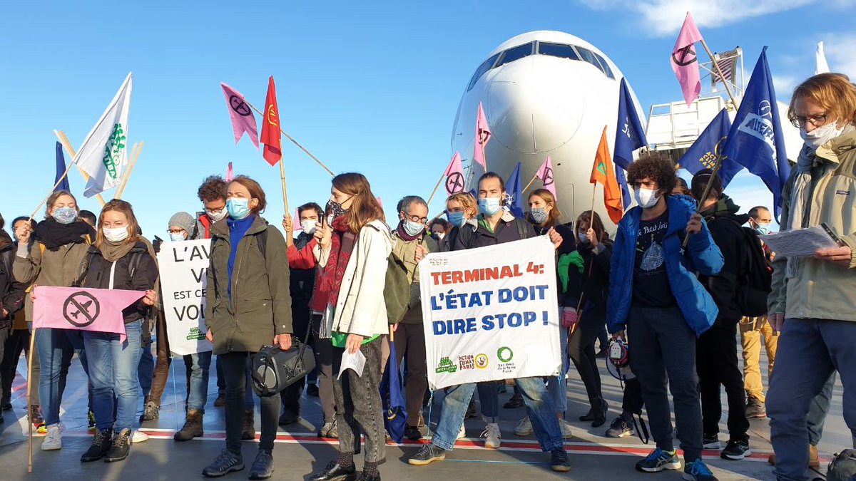 GP_Paris's tweet photo. 🔴ACTION EN COURS ! 
Nos militant.e.s sont présent.e.s à #Roissy pour la réduction du trafic aérien.
- Le gouvernement n’a pas les pieds sur terre, il est urgent qu’il atterrisse ! - 
#AvionsATerre #RoulonsSurLesAvions

Signez la pétition #NonAuTerminal4 : https://t.co/7fAaIIpehw https://t.co/AuYTNXU25a