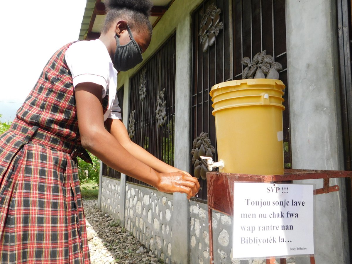 HaitiLibrary's tweet image. The Deschapelles Community Library is taking great precautions and following guidelines to prevent covid-19. Here a girl shows how she washes her hands and wears a mask before entering the Library. #Haiti #sistercities #Deschapelles #library photo credit: Besly Belizaire
