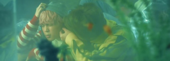 In the next scene we see Seokjin stabbing something into Jimin's ears. It isn't an earring but a pin which is interpreted as a sign of solidarity with refugees. It is believed that people wearing pins are harmless.People wearing pins if treated badly, they know they aren't alone