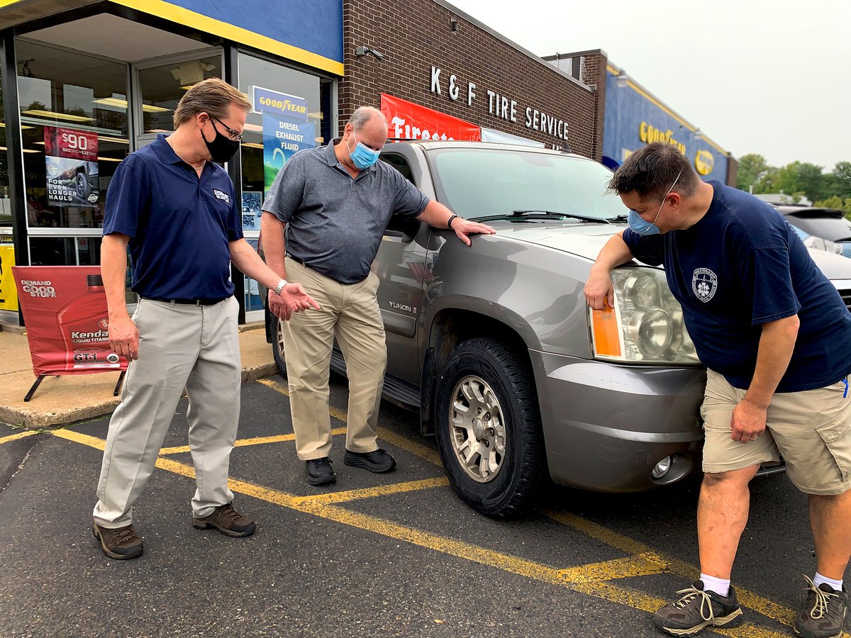 Jamie Haddon (right) of Doylestown with new Goodyear tires on his Yukon. Kershaw Fritz owner Dave Fritz (left) and John Donnelly, of Tire Hub Goodyear distributor locally. Haddon got 4 tires as part  "Helping Hoops" program honoring 1st responders during the COVID-19 pandemic.