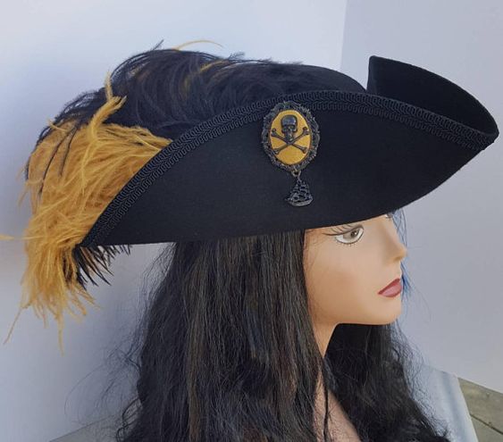 In place of a cockade (or just on the other side of the hat,) Perdita may have a decorative brooch that may or may not have a feather attached to it. Perdita picks up brooches all over the place & repurposes them not only for her hat but to spice up then sell for a profit.