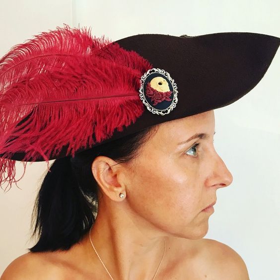 In place of a cockade (or just on the other side of the hat,) Perdita may have a decorative brooch that may or may not have a feather attached to it. Perdita picks up brooches all over the place & repurposes them not only for her hat but to spice up then sell for a profit.
