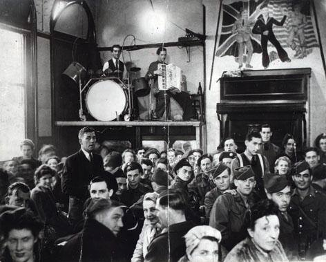 McrHistory's tweet photo. Why is Band on the Wall called Band on the Wall?

The enterprising landlady wanted space to get more drinkers in so she put the performers on a stage built into the wall, accessible by steps. The photo shows servicemen &amp; women frequenting the venue during the Second World War. https://t.co/TLGDZFWb7Y