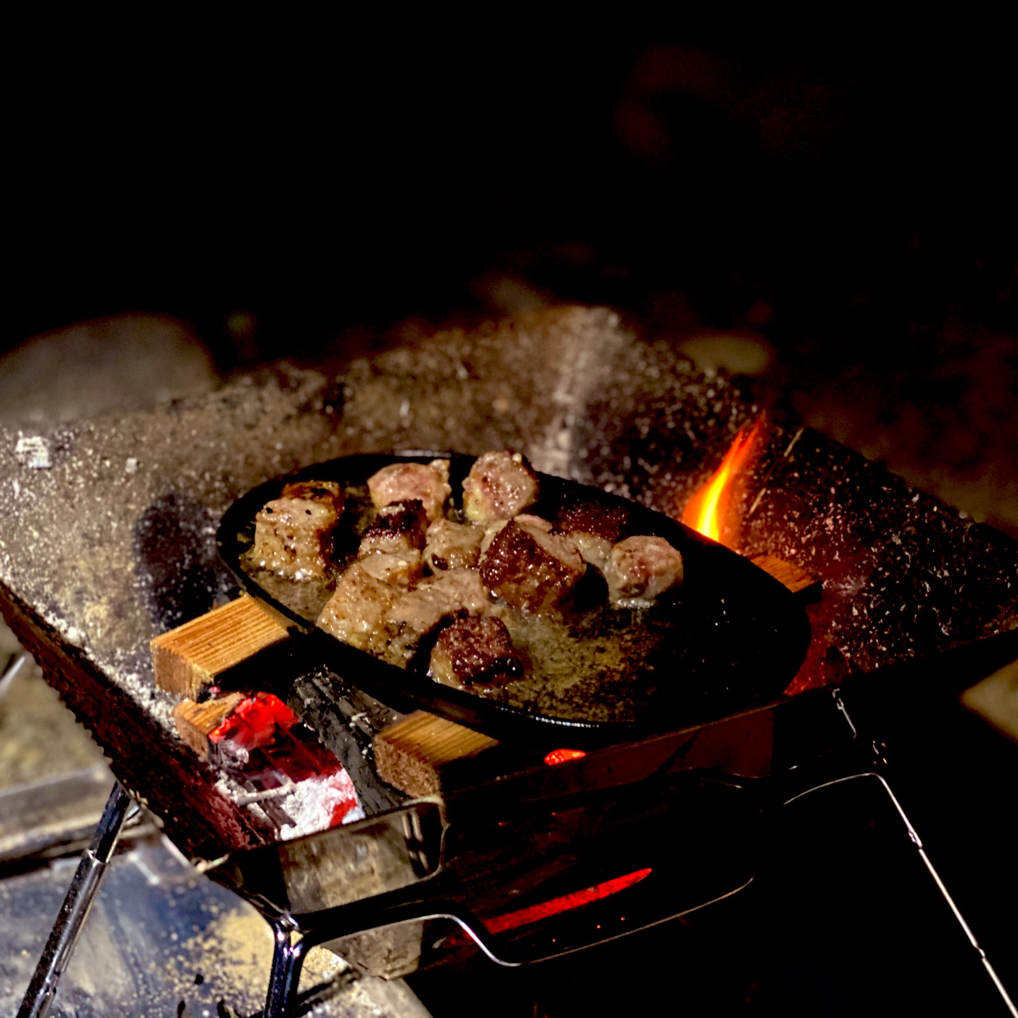 小原剛 ソロキャンvol 1のご飯 この日は焼き網忘れて肉は鉄スキレット使用 焼き鳥はトングで焼く 写真 サイコロステーキ ソーセージ アンガス牛肩ロースステーキ 焼き鳥 木台 ハンドル付きステーキ皿byニトリ バーベキューコンロ 焚き火台