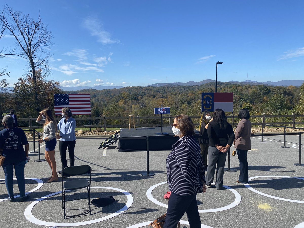 A crowd of about 25 waits for  @KamalaHarris and the program to start at University of North Carolina-Asheville, infront of a pretty scenic vista.Folks are separated by social distance circles and x toe marks.