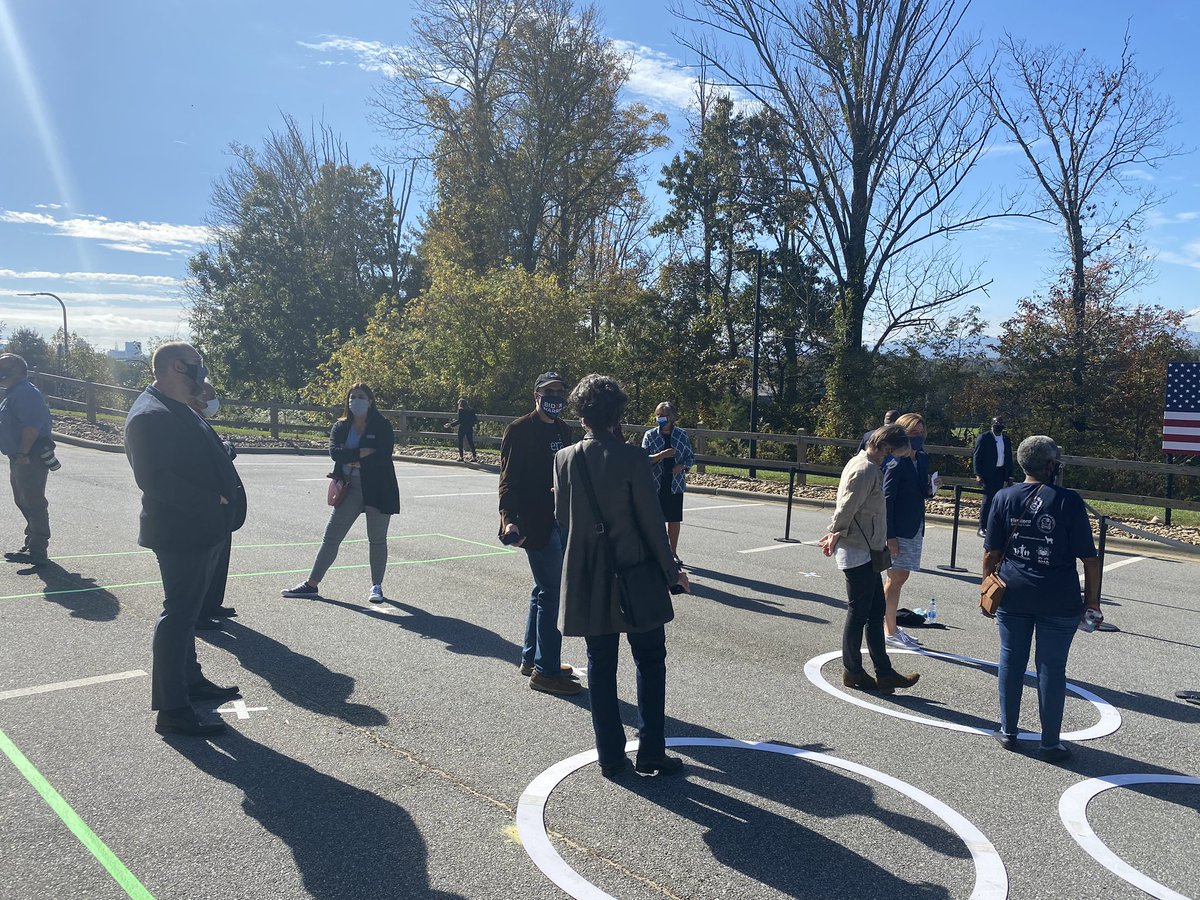 A crowd of about 25 waits for  @KamalaHarris and the program to start at University of North Carolina-Asheville, infront of a pretty scenic vista.Folks are separated by social distance circles and x toe marks.