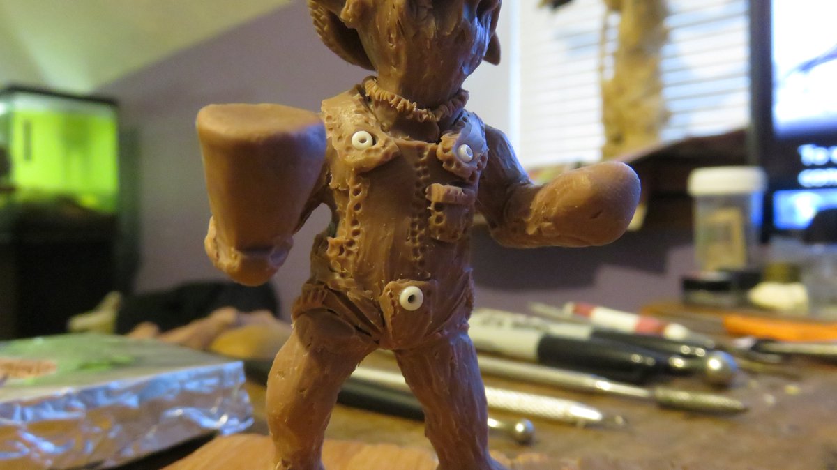 Next, I add a layer of clay. Then I start shaping and cutting away, and adding onto, and making detail, etc. He will have a pot plant in his right hand, and he will be politely passing a pipe full of pot, or a joint maybe. Working on his overalls right now. Yes, that's his beard.