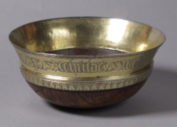 This is. This is a mazer, a maplewood bowl used as a drinking cup. Mazers were common across medieval Europe, ordered in the dozens, and tossed into fires when they cracked from use. But people LIKED maplewood, and dressed some mazers up with brass, silver, and gold metalwork.