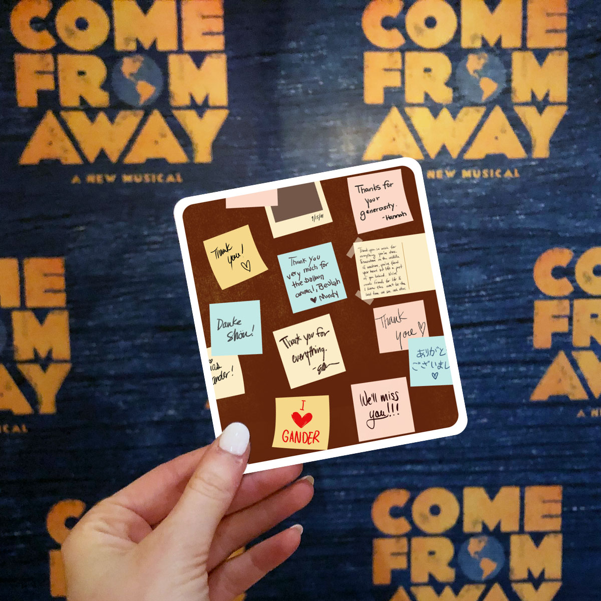 Holding up a Thank You card in front of a Come From Away backdrop 