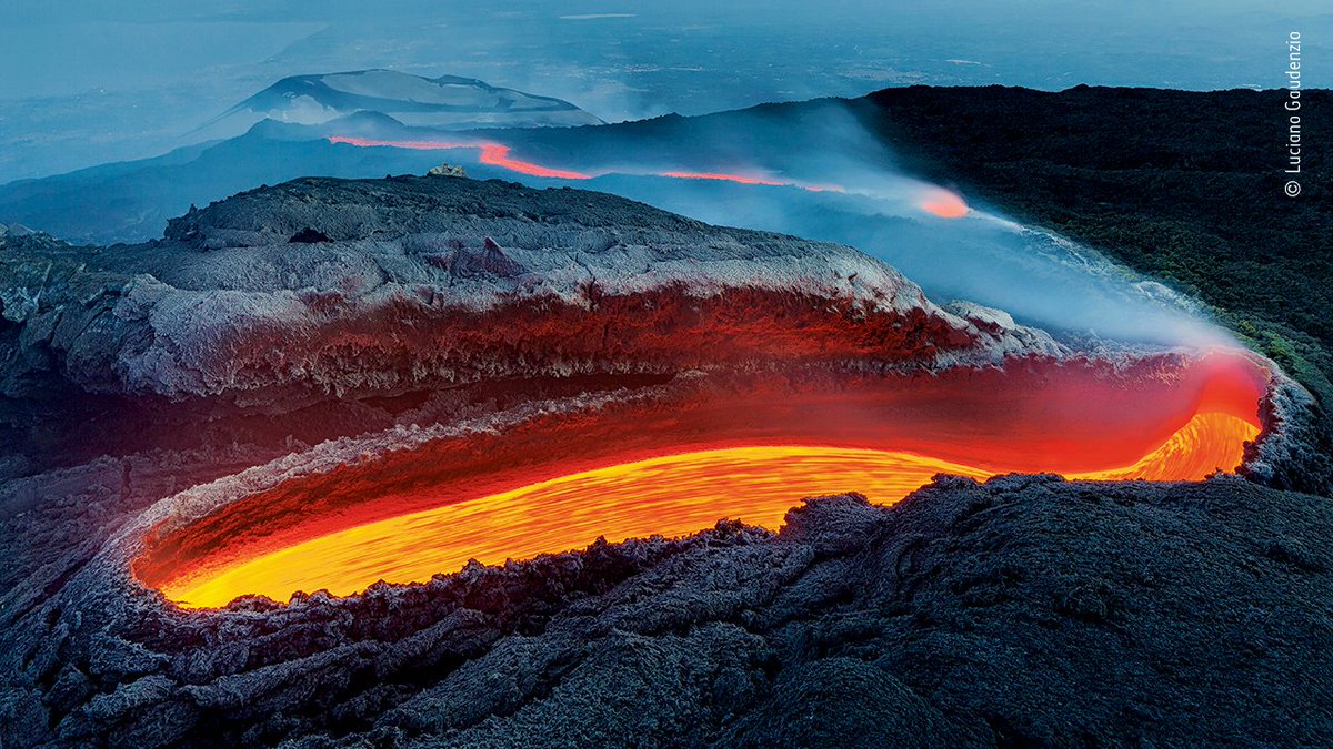 NHM_WPY's tweet photo. From a great gash on Mount Etna, lava flows within a huge lava tunnel, re-emerging as an incandescent red river, veiled in volcanic gases. Congratulations to Italy's Luciano Gaudenzio, #WPY56's winner in the Earth's Environments category. https://t.co/Lq2WVIIbQH