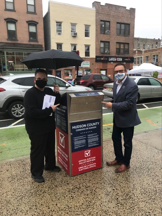 countyclerkhc's tweet photo. Neither rain nor snow nor sleet can stop City Clerk Sean J Gallagher from casting his vote while County Clerk Junior Maldonado helps keep him dry. You too, can drop off your ballot at City Hall located at 280 Grove Street in Jersey City. #HCVOTE2020 https://t.co/LlvRqReJbg