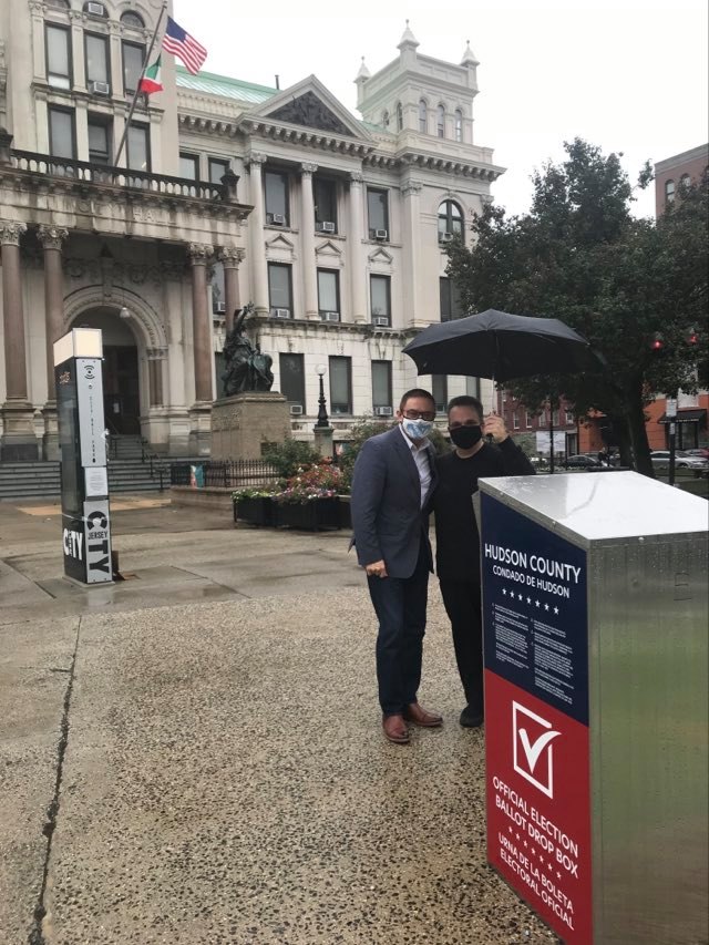 countyclerkhc's tweet photo. Neither rain nor snow nor sleet can stop City Clerk Sean J Gallagher from casting his vote while County Clerk Junior Maldonado helps keep him dry. You too, can drop off your ballot at City Hall located at 280 Grove Street in Jersey City. #HCVOTE2020 https://t.co/LlvRqReJbg