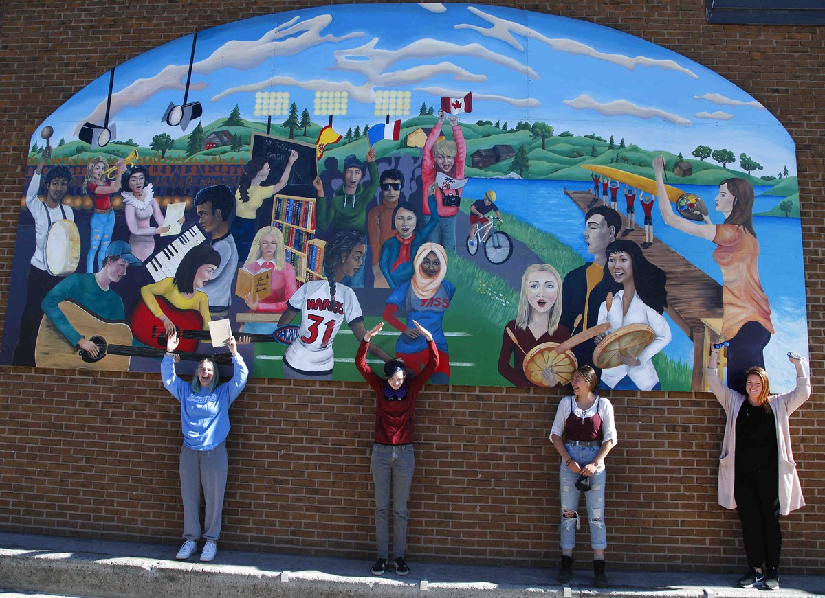 cliffskarstedt's tweet photo. Students Rowena Burke, Austin Bowie, Jade Showers, who were painted in a colourful mural, next to visual arts teacher Angie Zavitz @TASGriffins @kprschools during the unveiling of a mural representing the school's diverse community in #PTBO https://t.co/W7w3xKYYus
